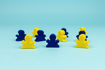 Plastic people figures of the Ukrainian flag colors on the blue background. Blue and yellow meeples. Social concept. Board game figures.