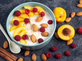Milk oatmeal with almonds, raspberries and peach. Healthy and tasty breakfast