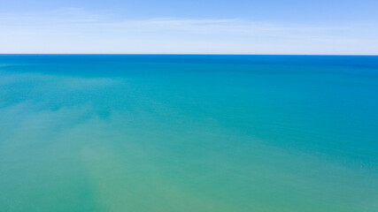 Aerial view of the blue waters of the Mediterranean Sea and specifically of the Tyrrhenian Sea from Sicily. Sunlight is reflected on the surface of the water. Sky and clouds are on background.