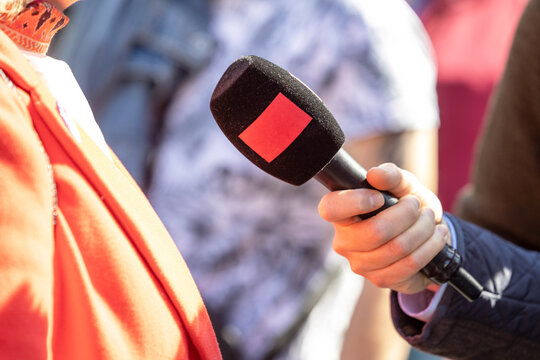Journalist holding microphone making media, street or vox popoli interview