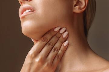 Cropped shot of young blonde woman with throat ache touching enlarged lymph nodes under jaw on her...