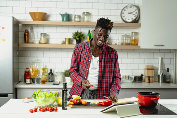 African man preparing food in modern kitchen. Handsome chef cooking pasta