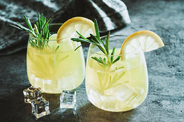 Cold cocktail, lemonade with lemon sliced, rosemary plant on dark concrete background. Drink photo - obrazy, fototapety, plakaty