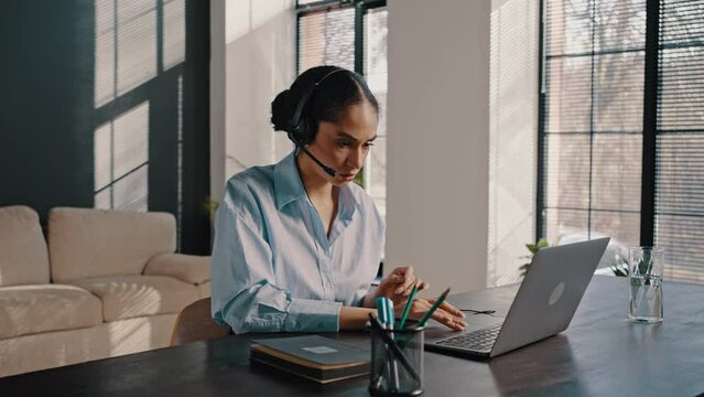 Confident business woman wearing audio headset during online conference via video link on laptop
