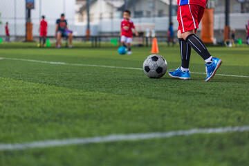 Children playing control soccer ball tactics cone on grass field with for training background Training