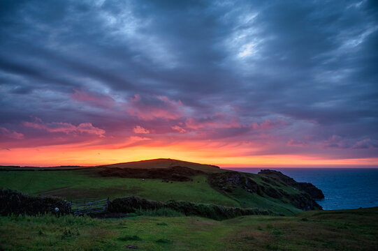 A view of lush cliffs along the coastline of Cornwall at sunset