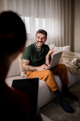 Fototapeta premium Happy young man with tattoos working from home, talking to his wife.