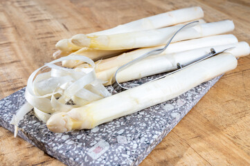 How to peel asparagus, spring season, new harvest of Dutch, German white asparagus, bunch of raw white asparagus