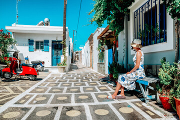 Woman in long dress sitting on bench in greek village Koskinou in Rhodes island in Greece
