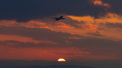 Fototapeta na wymiar Plane flying over a sunrise