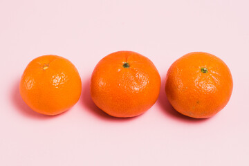 Tangerines on pink paper background with copy space.