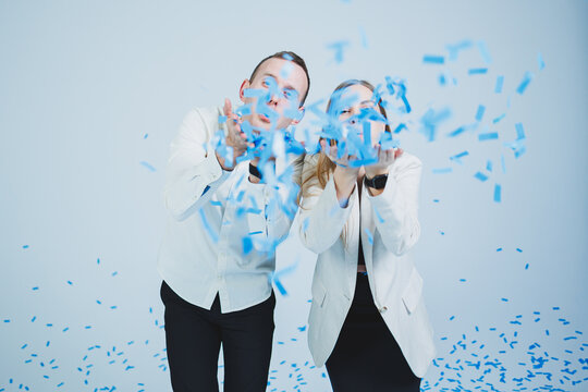 Young happy married couple hugging in blue confetti. A couple in love rejoices and has fun. Gender photo session