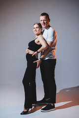 Cheerful happy young couple hugging on a plain background. A stylish man and a woman in love are tenderly embracing.