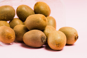 Kiwi in plastic packaging on a pink background. Concept of earth day, zero waste and recycling.
