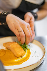 Chef cooking Roasted salmon steak with pumpkin cream on restaurant kitchen
