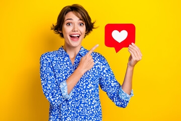 Photo charming impressed woman dressed blue blouse pointing finger heart like card isolated yellow color background