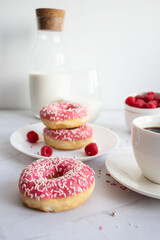 Donuts with coffee and milk. 
Donut with pink frosting 