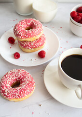 Donuts with coffee and milk. 
Donut with pink frosting 