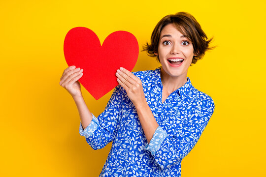 Photo of impressed funny lady wear print shirt rising red heart isolated yellow color background