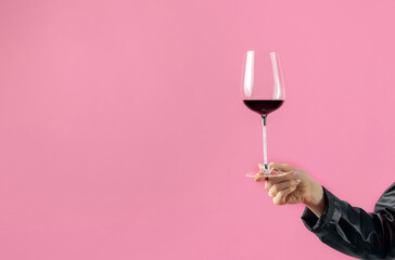 attractive woman taking glass with wine from floor pink background.girl in black leather and...
