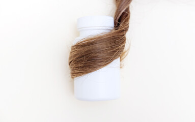 hair care and treatment concept.hair thread isolated with many pills tablets from bottle or in wine glass.curly natural no dye healthy strong hair.vitamins scattered on surface or wooden round board