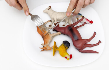 farm animals plastic toys in white plate and woman female hands holding knife and fork pretending...