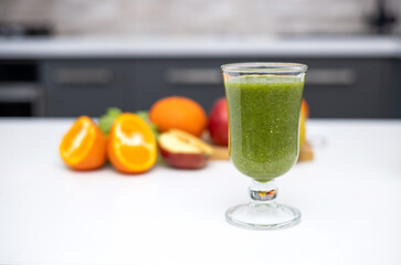healthy smoothie in glass and fruits all around on wooden board kitchen table and background.slim fit weight loss take natural vitamins.bio tangerine celery spinach kiwi and apple.mashed fruits 