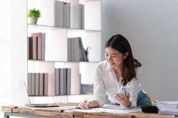 Smiling Asian Banker makes financial report and studies annual figures, analyzes profits. Accountant checks status of financial