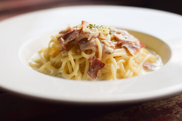 Spaghetti Carbonara in white dish on wood table