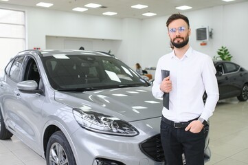 Smiling, friendly car seller standing in car salon.