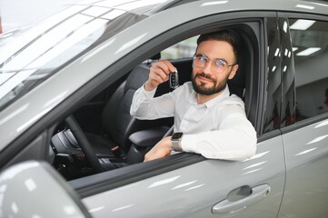 Happy caucasian man in formal wear getting inside luxury modern car for testing interior before purchase. Concept of dealership, selling and purchase