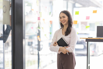 Business female employee with many conflicting priorities arranging sticky notes commenting and brainstorming on work priorities colleague in a modern office.
