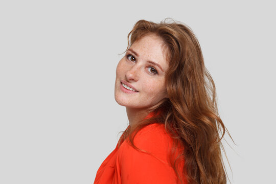 Healthy cute redhead woman with long healthy ginger curly hair posing on white studio wall background