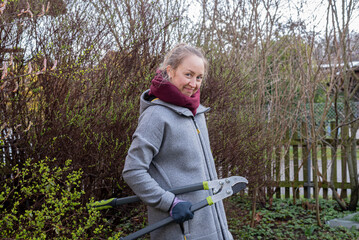 Portrait of a happy woman standing in the garden with tools.	