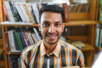 Happy smart indian or arabian guy, mixed race male, university student, in the library