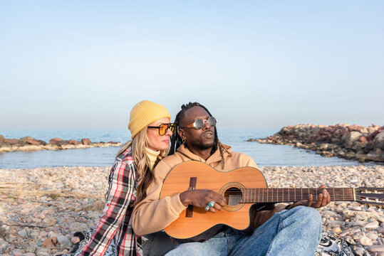 Happy diverse friends with guitar on beach