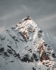 New snow in rocky mountains at a beautiful winter sunset scenery with high peaks.