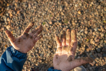 small children's hands in the mud and sand close-up, on the playground, while walking, selective focus