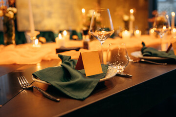 Luxury table setting for a celebration in a restaurant. Dark tones of orange and green are the colors of the holiday. Tableware and catering for the holiday