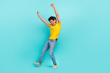 Full body photo of delighted carefree man raise fists dancing listen music isolated on turquoise color background
