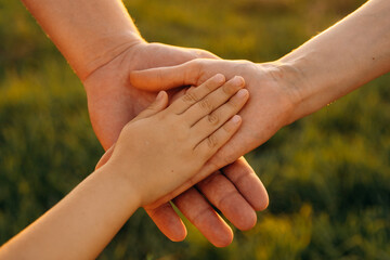Mom dad and child holding hands together during a walk in summer. Family hands and adult support. A...