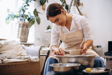 Woman working on pottery wheel creating a bowl