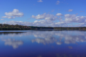 A calm sunny day with a view across Eccup Reservoir creating stunning reflections of blue sky and white clouds, Leeds, England, West Yorkshire, UK. 