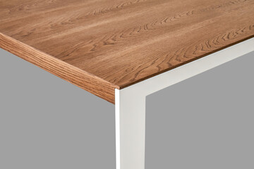 Minimalism style dining table with thin wooden table top of toned oak veneer on white metal legs closeup