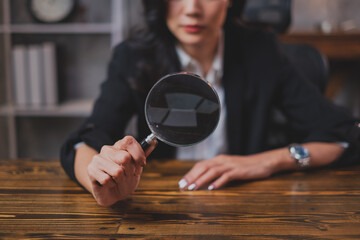 A Female manager is holding a magnifying glass. Concept of searching document, hiring employees, browsing data of company, online research, marketing inspection or analysis. Using lens to focus profit