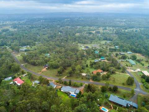 Aerial view of houses and properties in rural residential area on misty overcast morning in summer