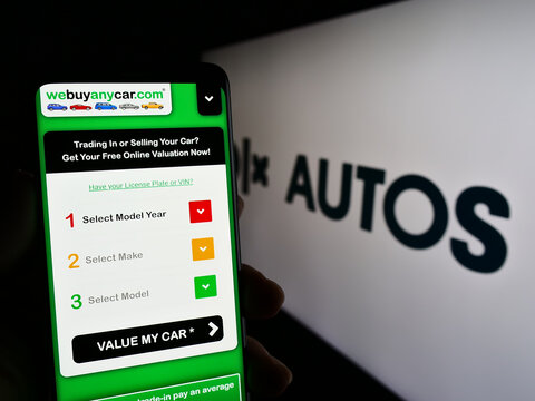 Stuttgart, Germany - 03-24-2023: Person holding cellphone with web page of Dutch car trading company OLX Global B.V. on screen in front of logo. Focus on center of phone display.