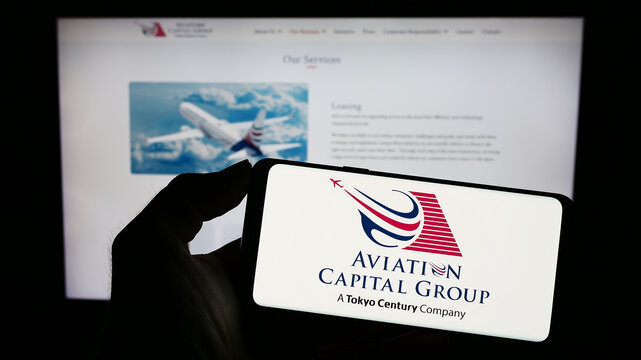 Stuttgart, Germany - 03-24-2023: Person holding cellphone with logo of American leasing company Aviation Capital Group LLC on screen in front of webpage. Focus on phone display.