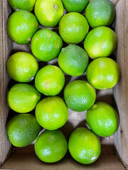 Close-up: limes in a wooden box.  Green citrus fruits.