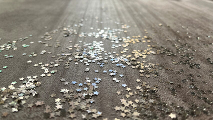 Star shaped silver glitter sparkles shining on marble background in the sun with shadows. Background